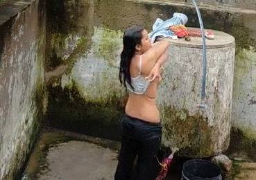 Indian village girl bathing near water tank outdoor